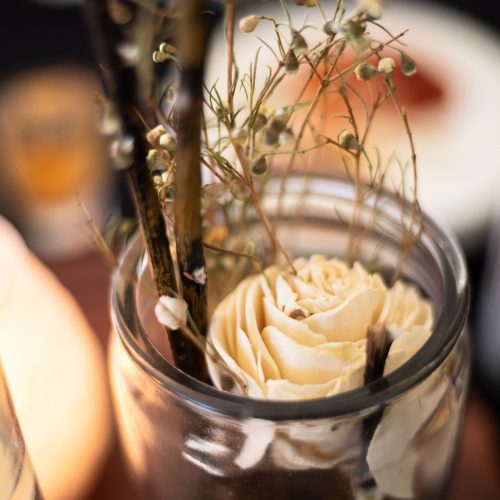Table decor with white rose inside jar with baby's breath and sticks